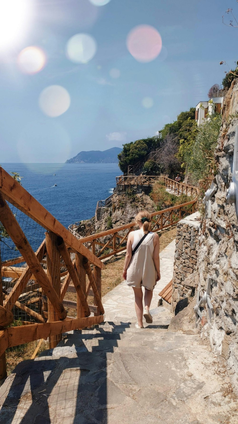 a woman walking down a stone path next to the ocean