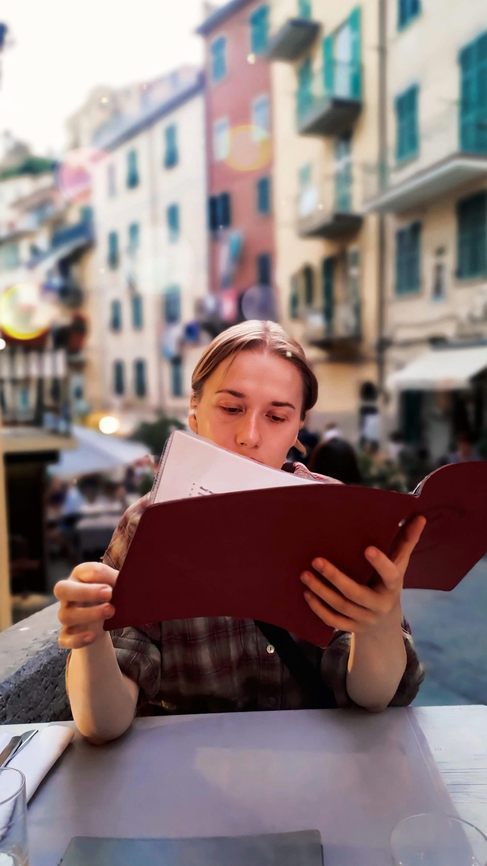 a woman sitting at a table reading a book