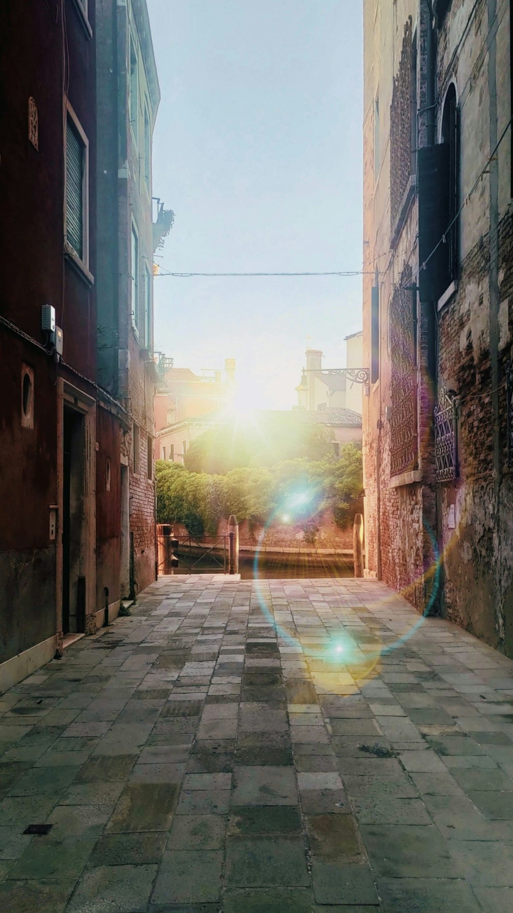 the sun is shining down on a narrow street