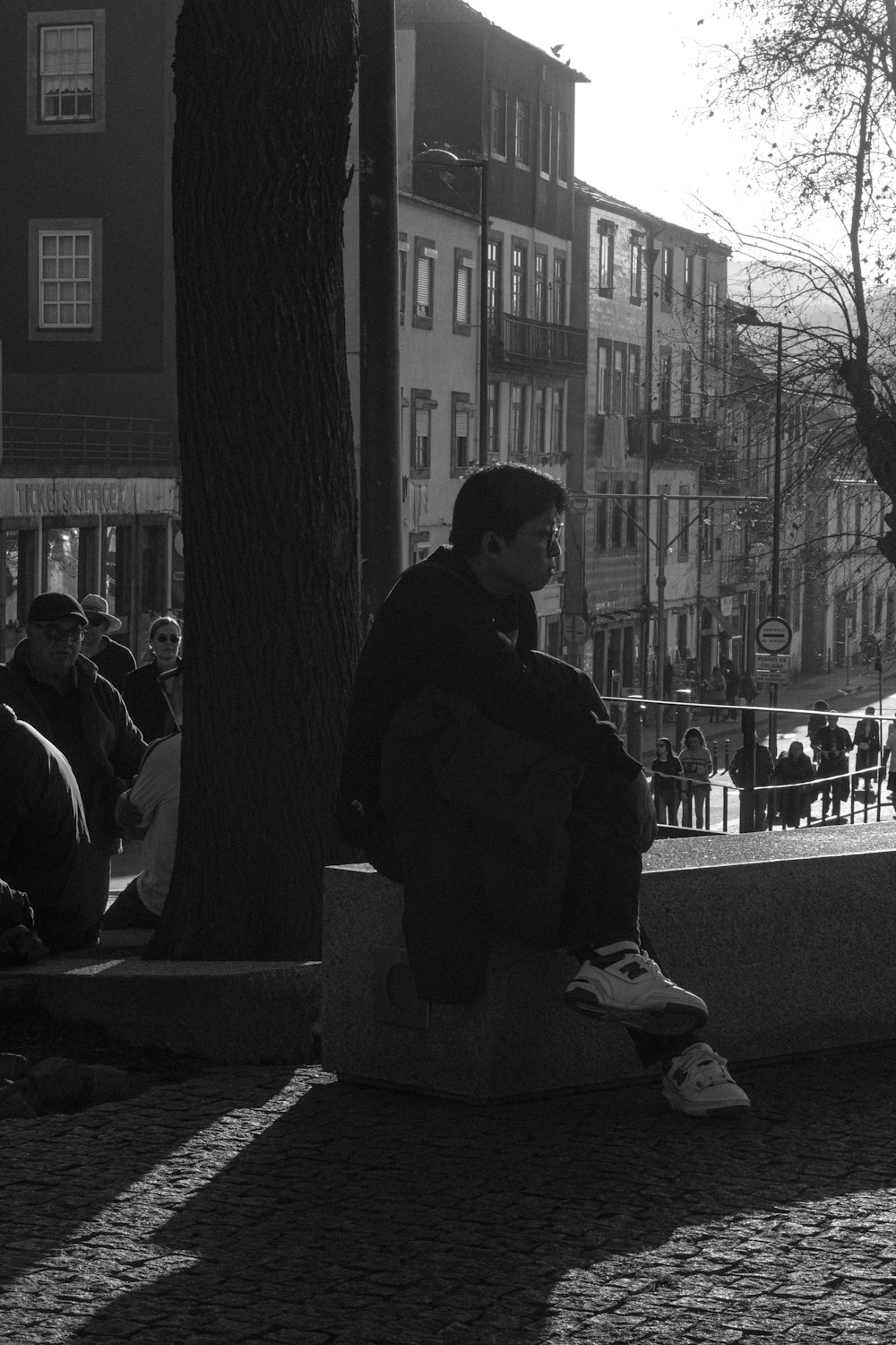 a man sitting on a bench next to a tree