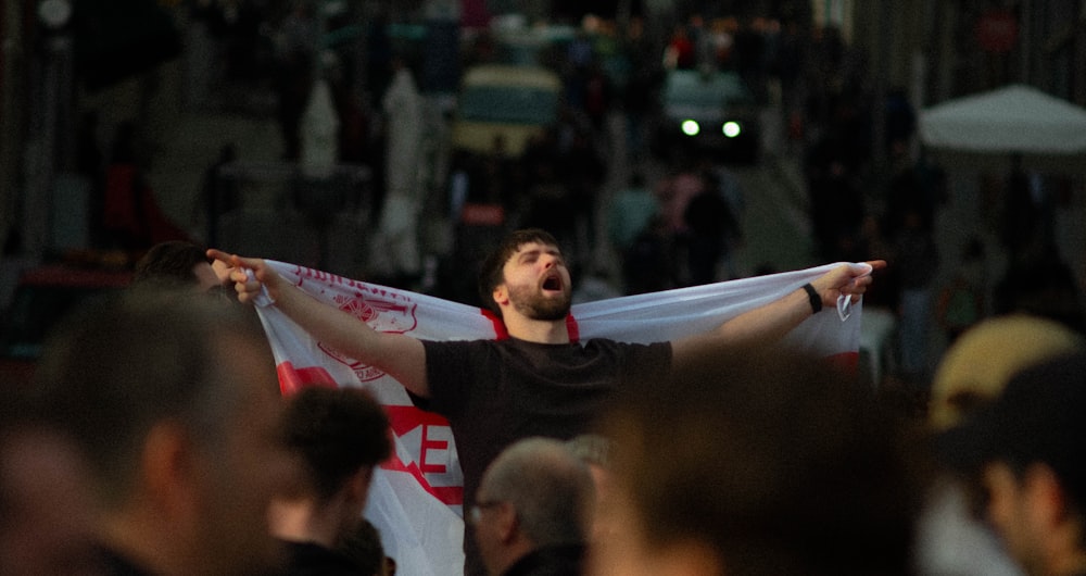 un uomo che tiene una bandiera bianca e rossa in mezzo alla folla