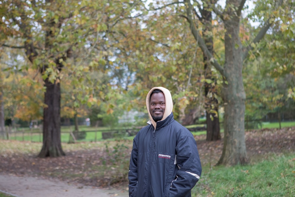 a man standing in a park with trees in the background