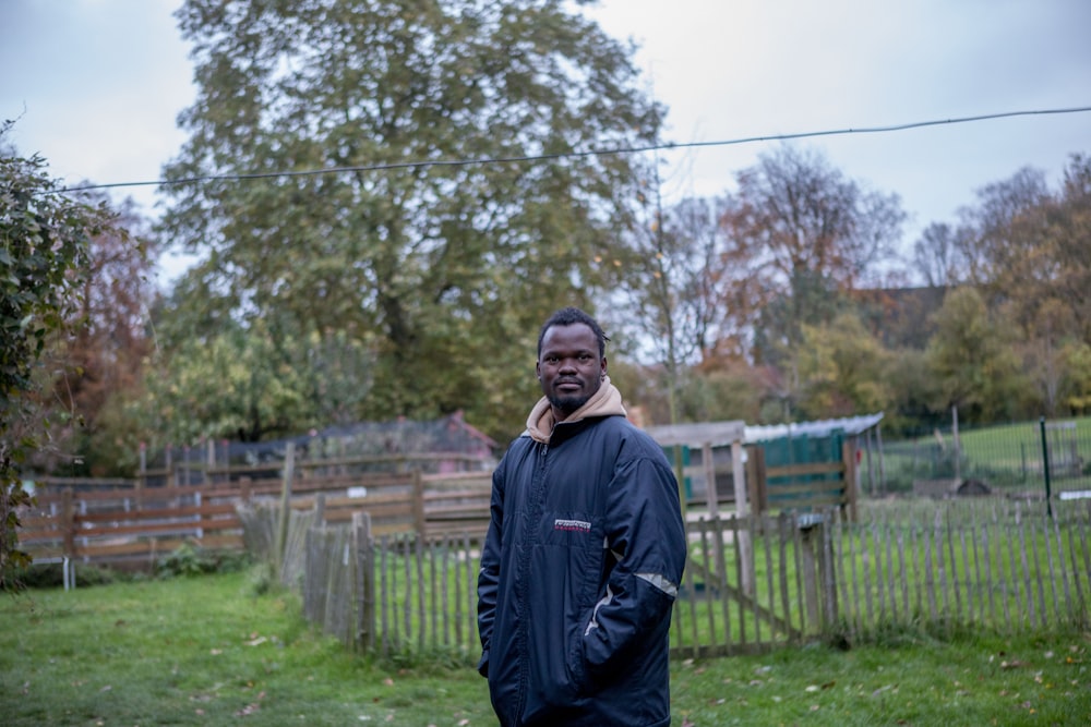 a man standing in a field with a cell phone to his ear