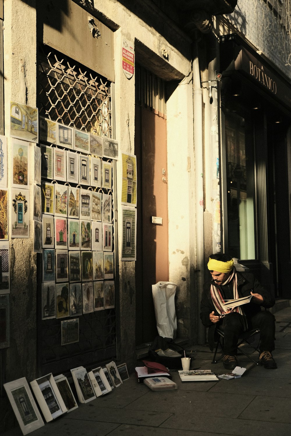 a man sitting on a sidewalk reading a newspaper