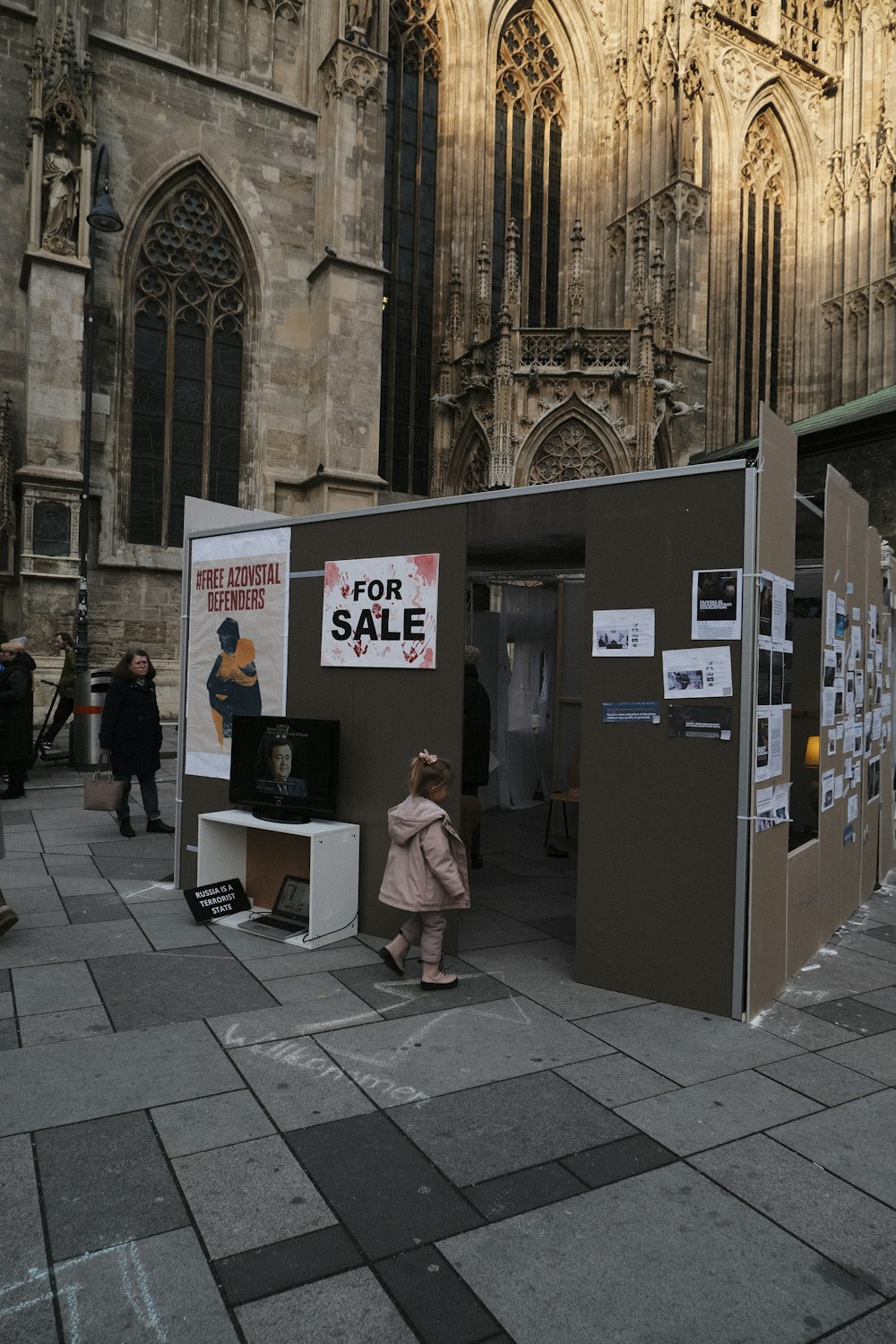Une femme passe devant un stand avec un panneau de vente dessus