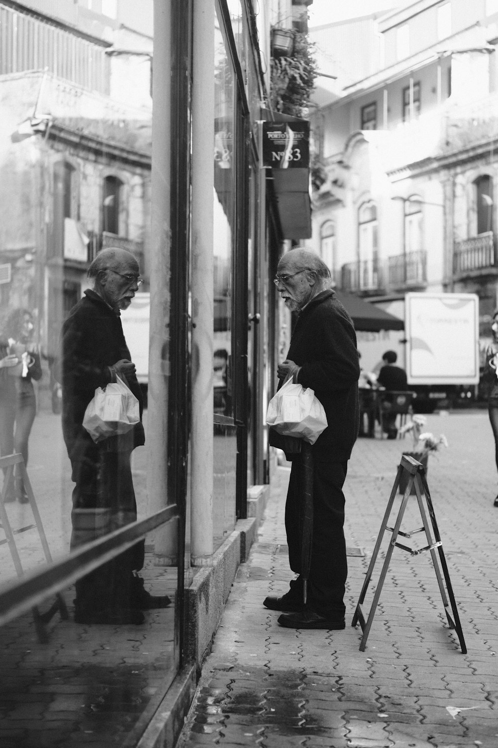 a black and white photo of a man looking in a window