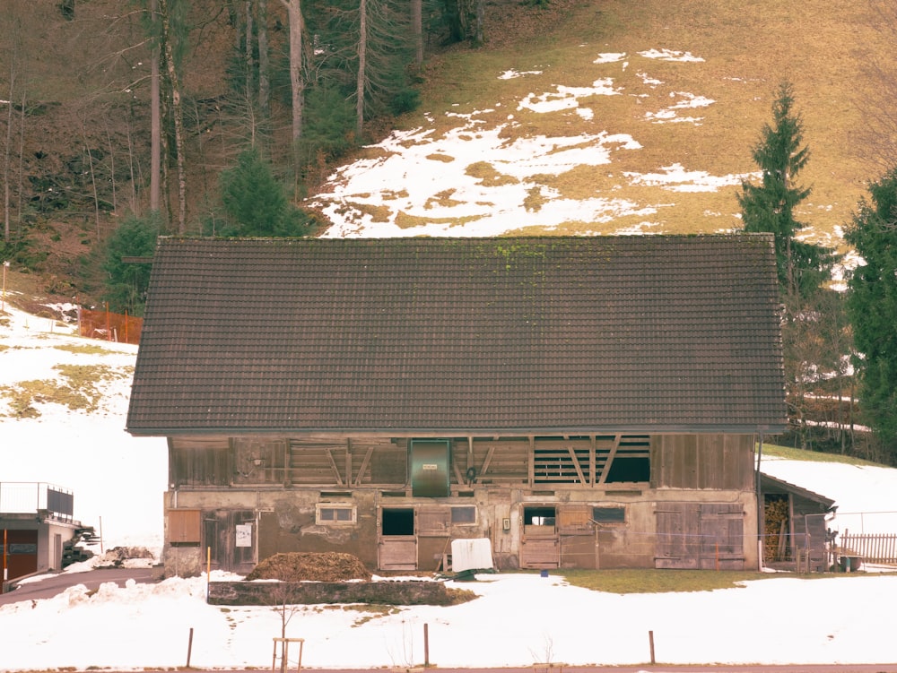 an old barn in the middle of a snowy field