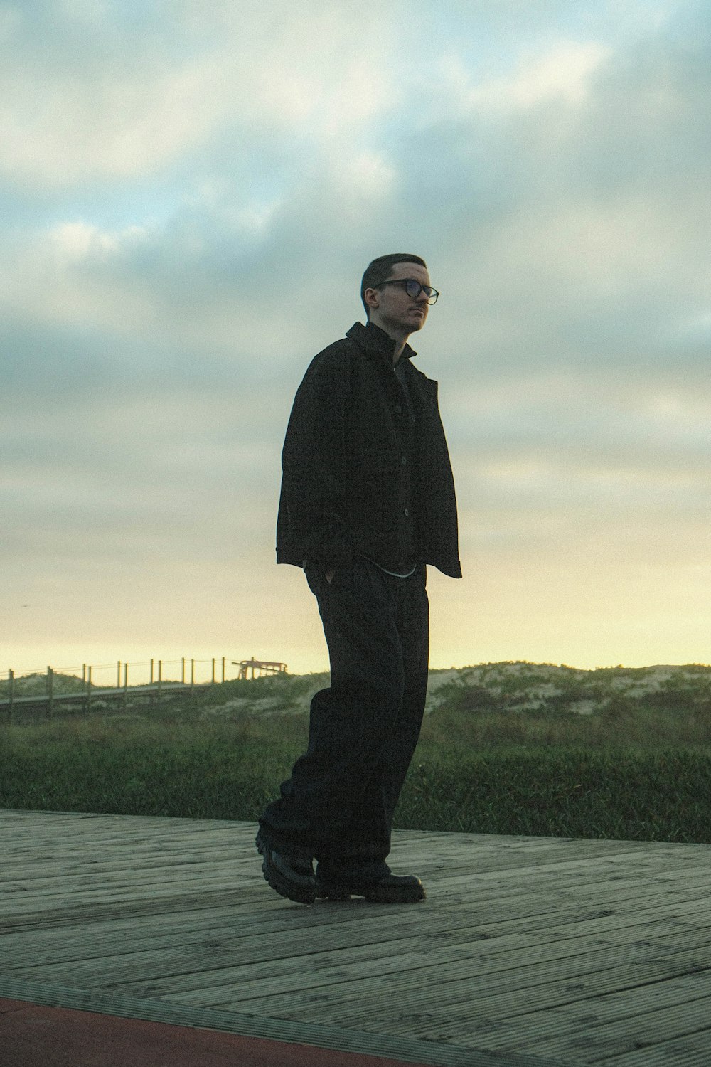 a man standing on a wooden deck with a skateboard