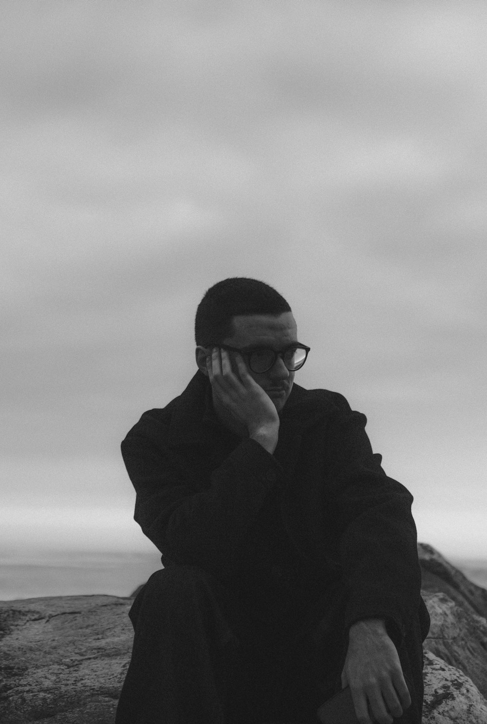 a man sitting on a rock talking on a cell phone