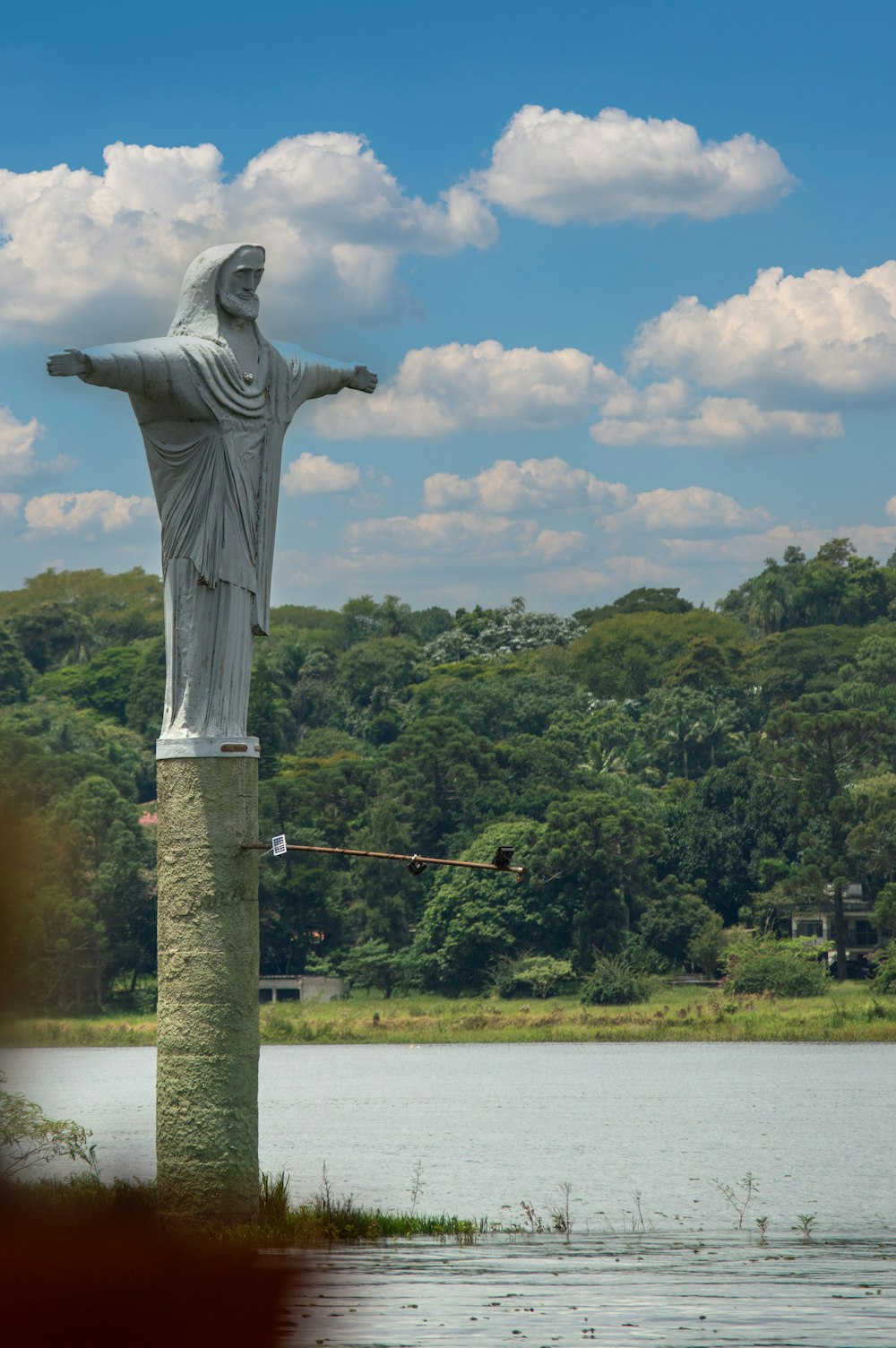 a statue of jesus on a pedestal in front of a body of water