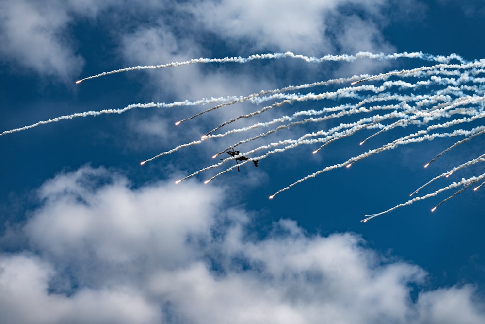 a group of jets flying through a cloudy blue sky