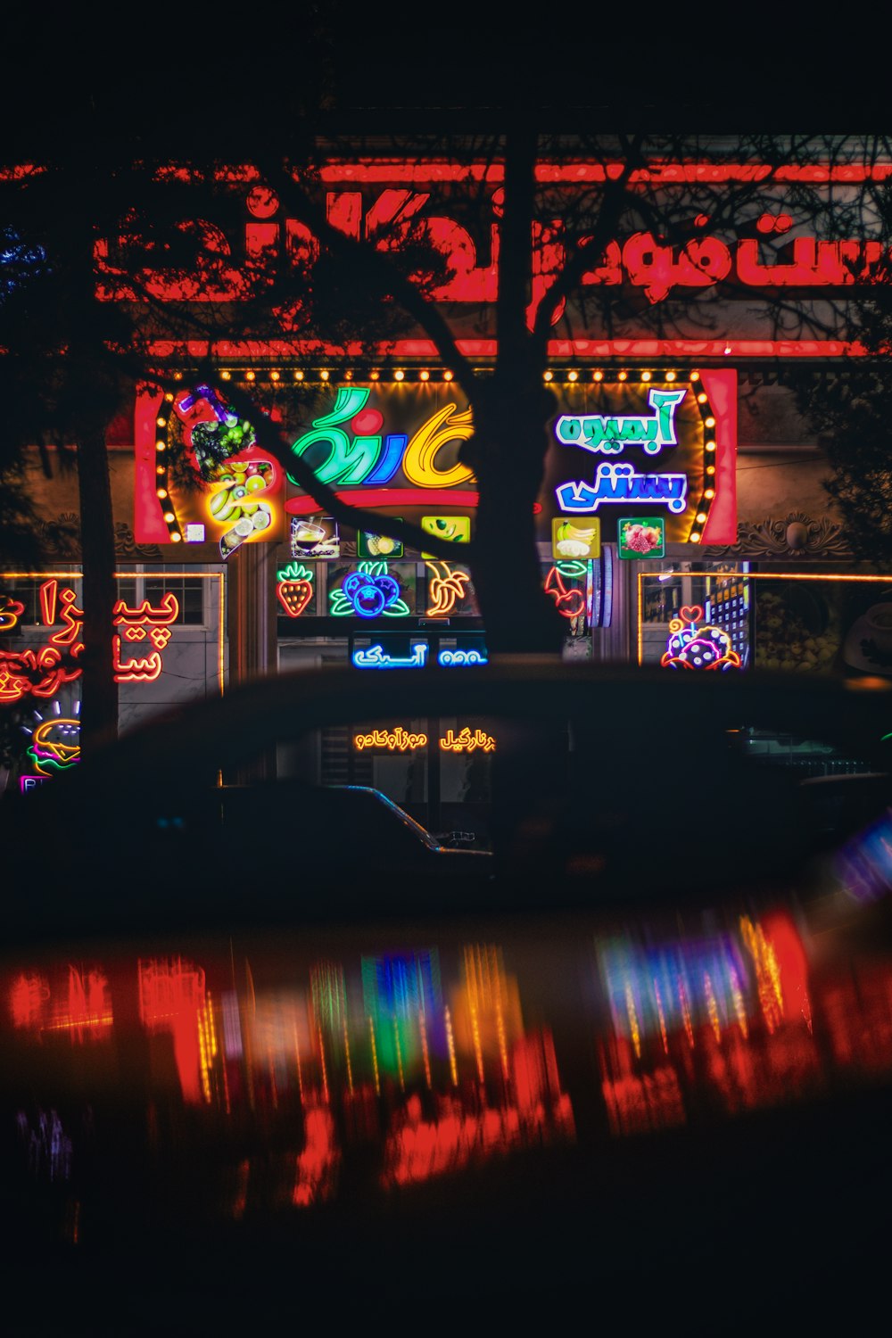 a car parked in front of a building with neon signs