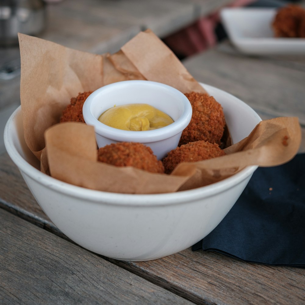 a white bowl filled with fried food on top of a wooden table