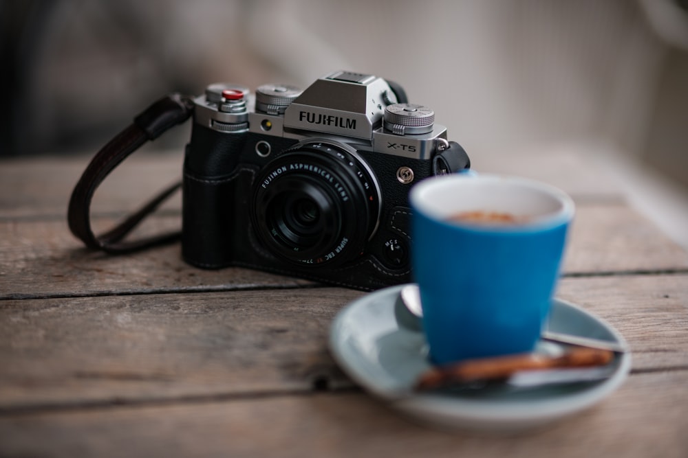 a camera sitting on top of a wooden table next to a cup of coffee