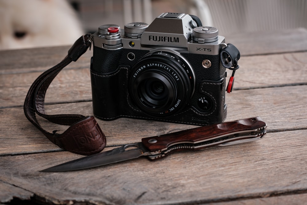 a camera and a knife on a wooden table