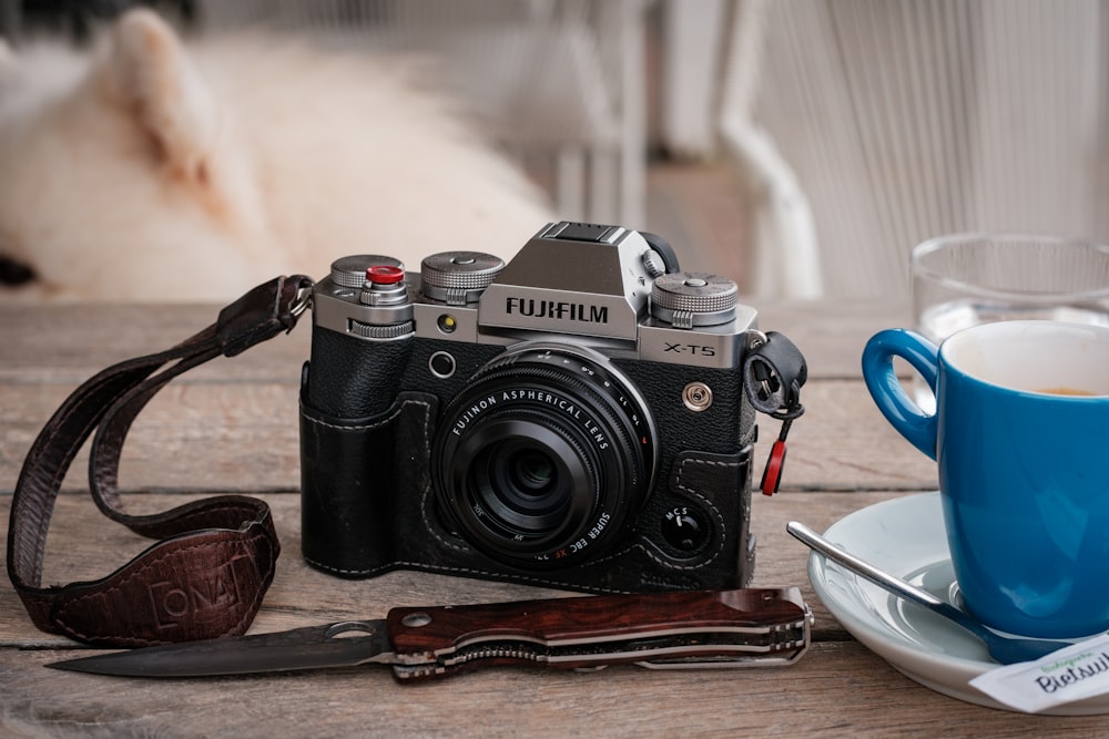 a camera sitting on a table next to a cup of coffee