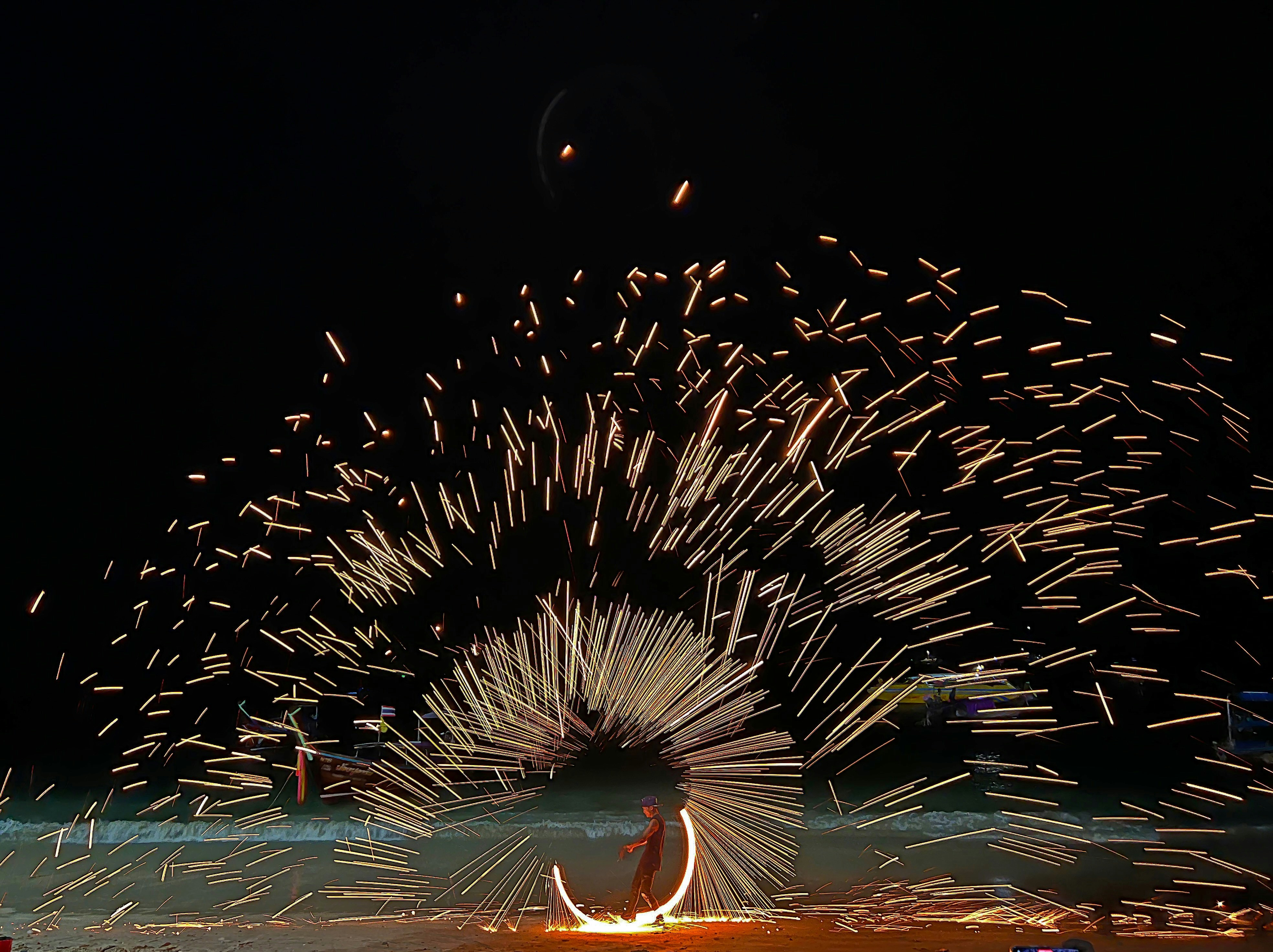 a man sitting on a surfboard in front of a firework display