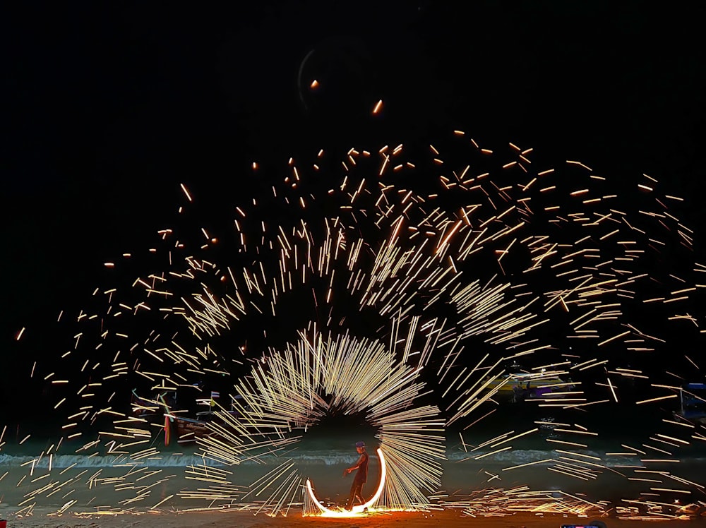 a man sitting on a surfboard in front of a firework display