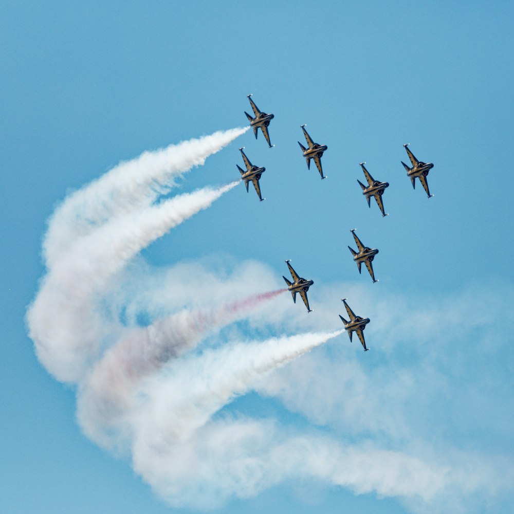 a squadron of fighter jets flying through a blue sky
