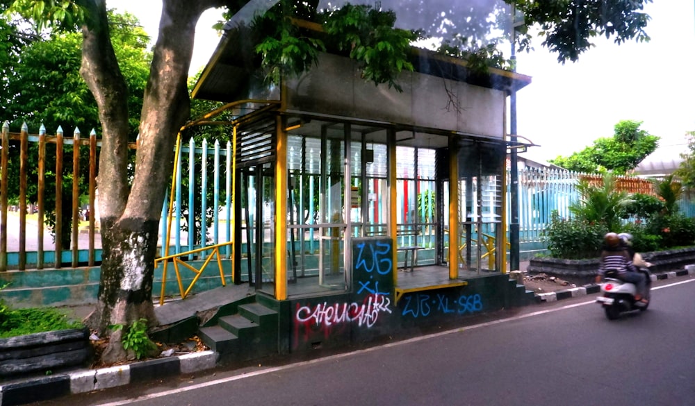 a man riding a motorcycle past a building with graffiti on it