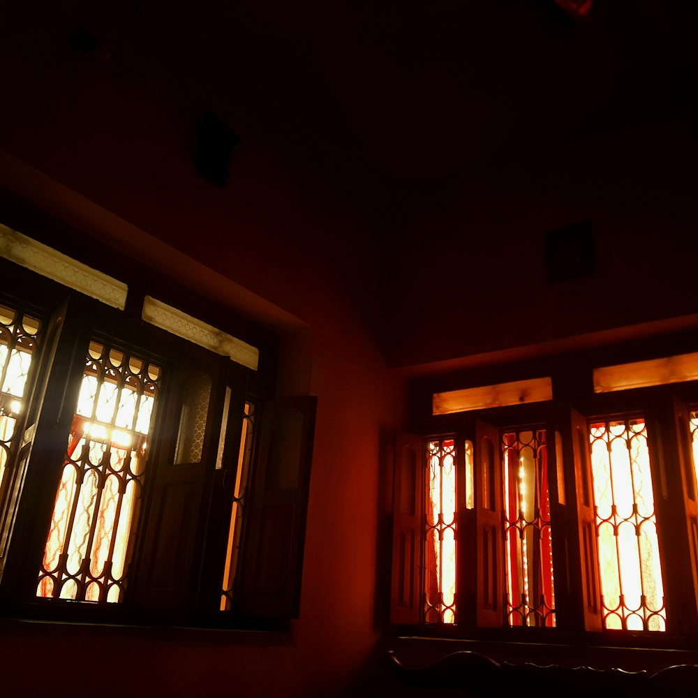 a dark room with three windows and a clock on the wall