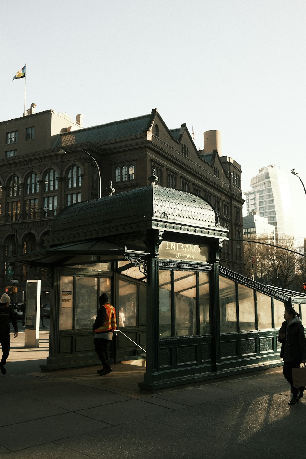 a group of people walking down a sidewalk next to a train station