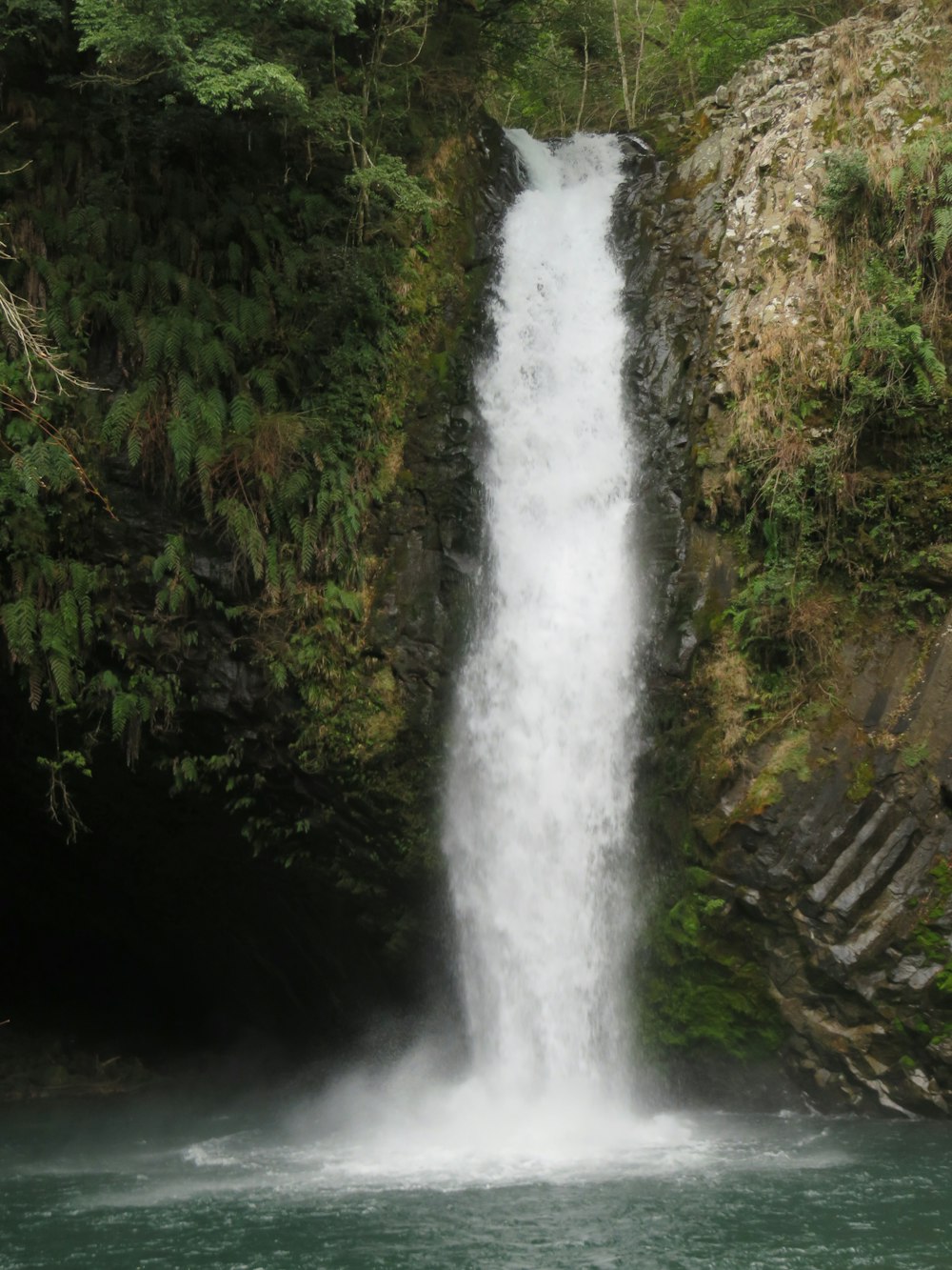 a waterfall with a man standing in front of it