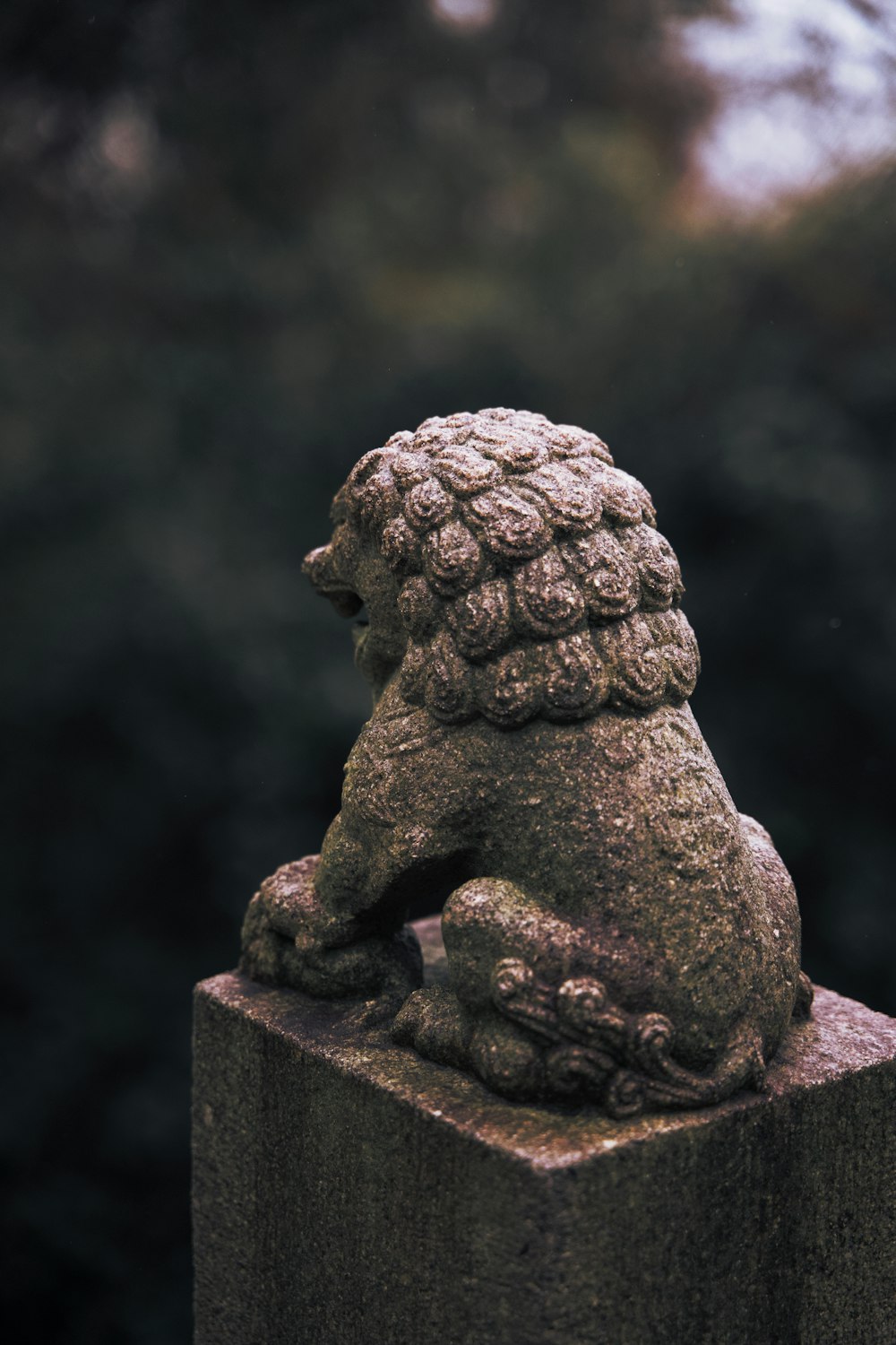 a statue of a lion sitting on top of a wooden post