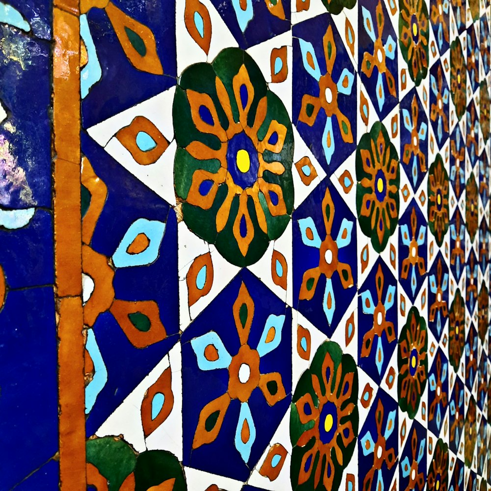 a close up of a tiled wall with flowers on it