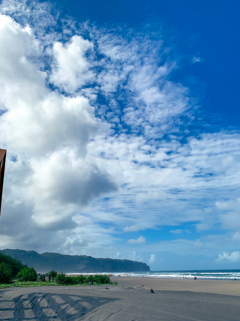 a view of a beach with a blue sky and white clouds