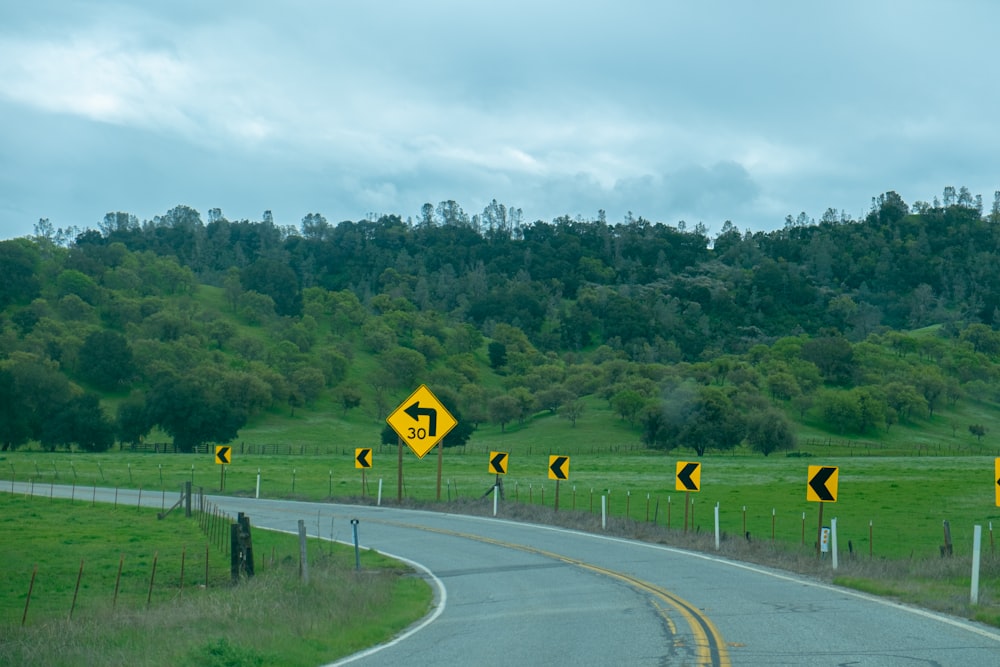 a curved road with yellow and black street signs