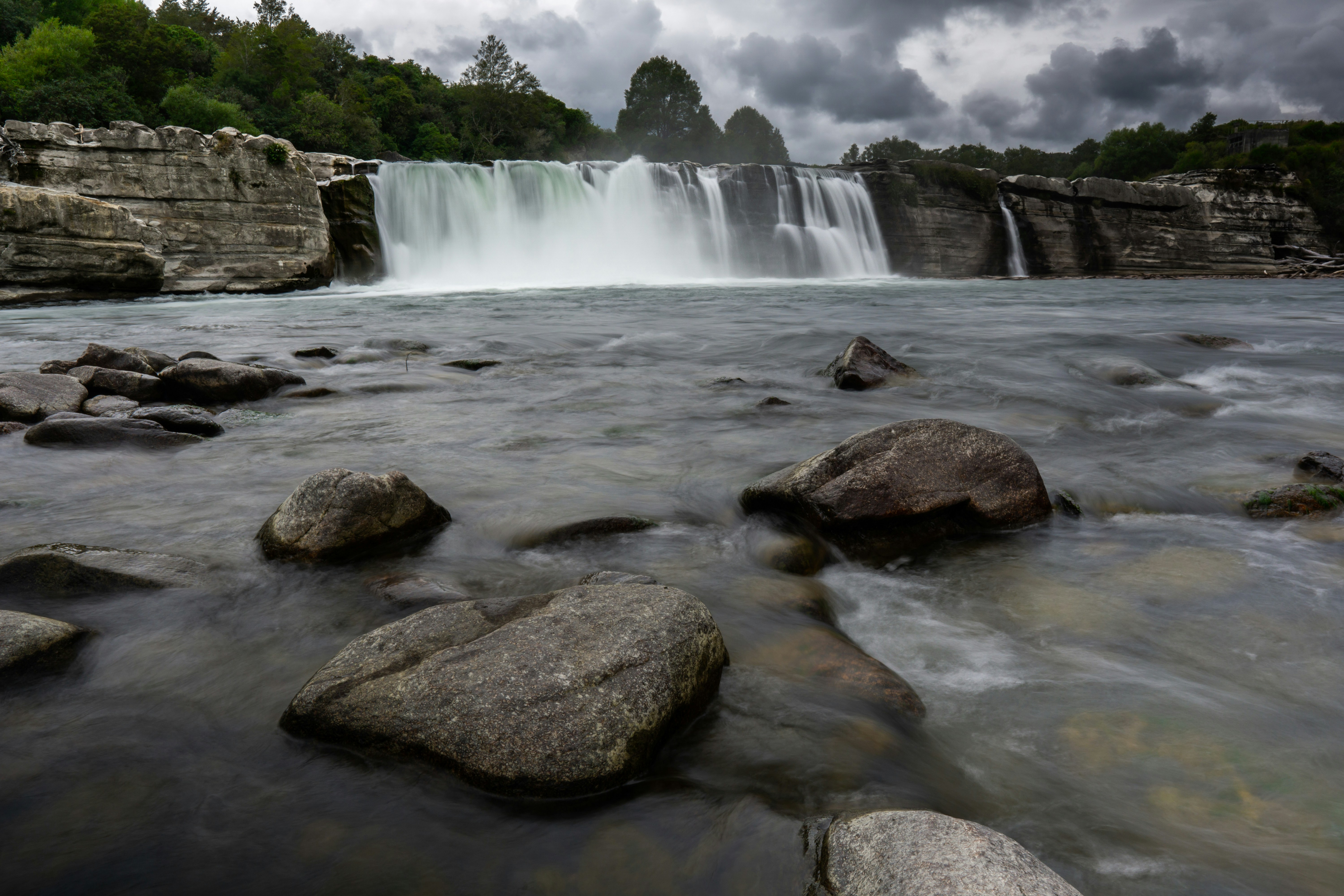 a waterfall with a large amount of water coming out of it, This long-exposure photo was taken at Maruia Falls, near Murchison in New Zealand