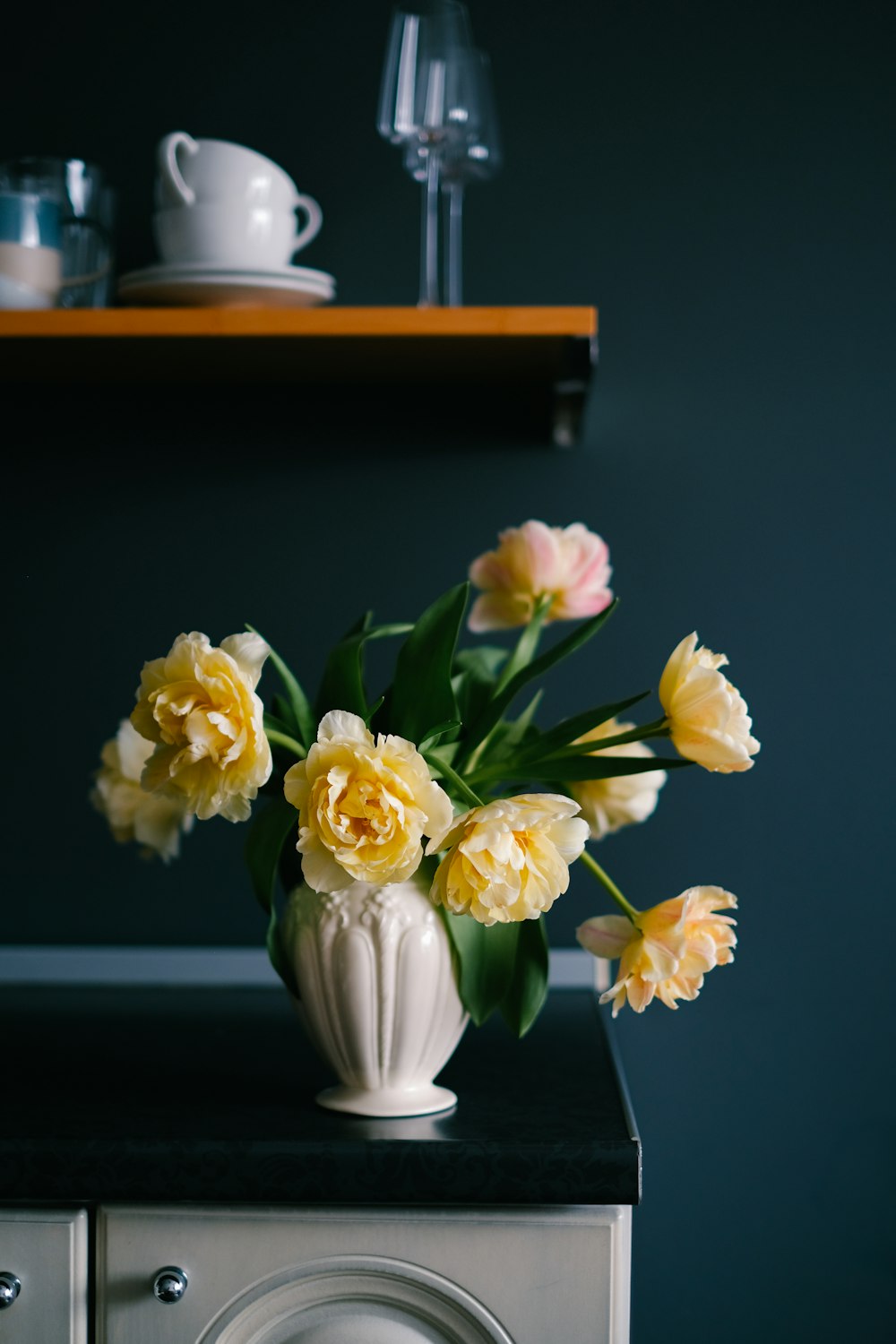 a vase of yellow flowers sitting on top of a washing machine