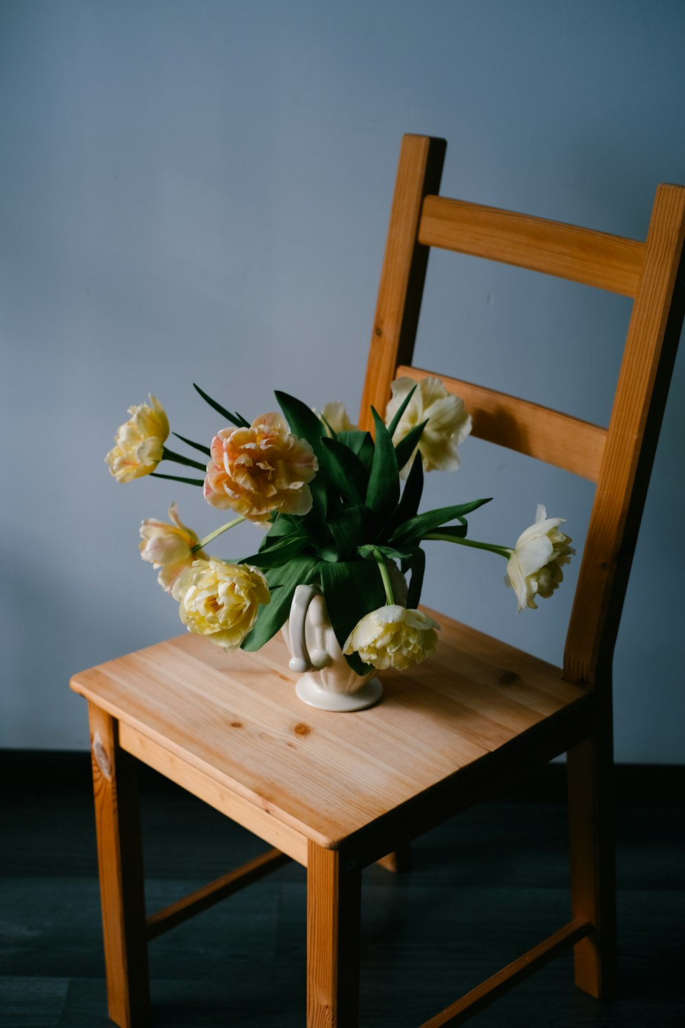 a wooden chair with a vase of flowers on top of it