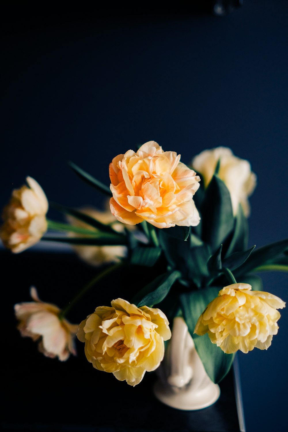 a white vase filled with yellow and orange flowers