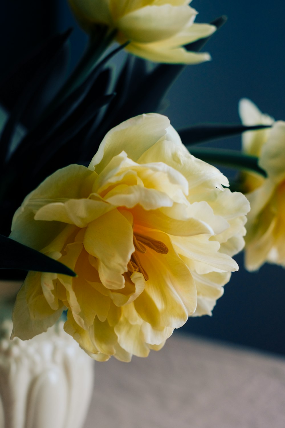 a white vase filled with yellow flowers on top of a table