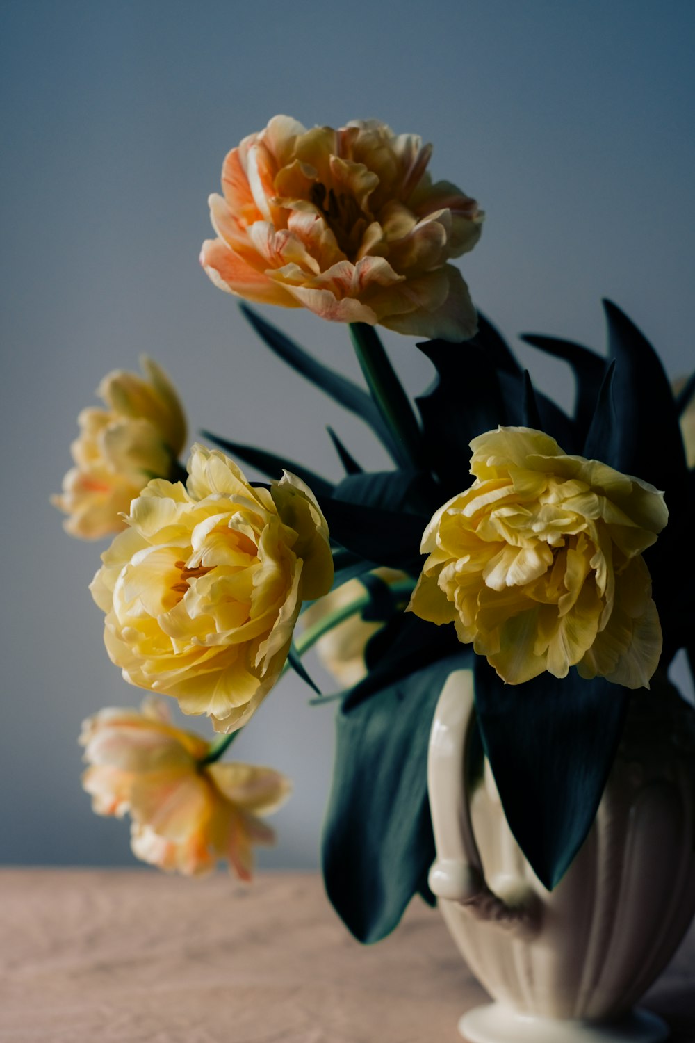 a white vase filled with yellow and orange flowers