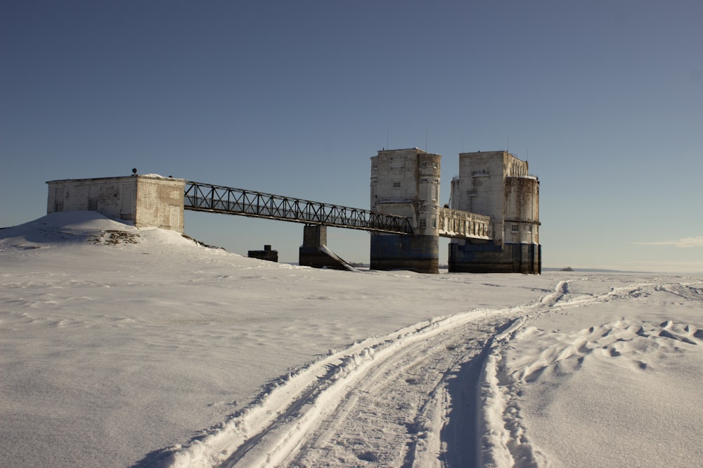 a bridge over a snowy field with tracks in the snow