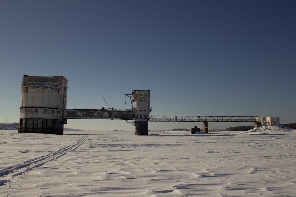 a bridge over a snow covered field on a sunny day