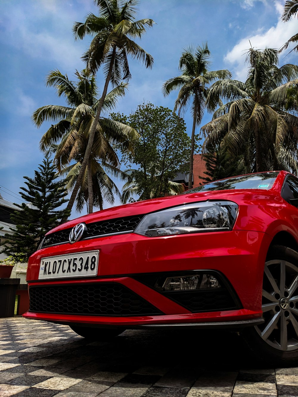 a red car parked in front of palm trees