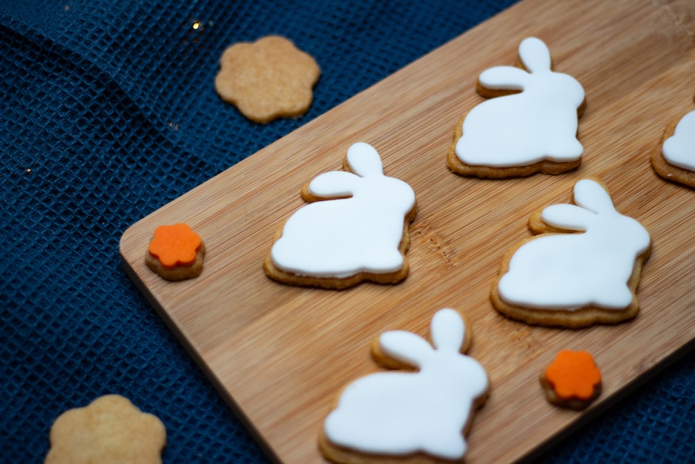 a wooden cutting board topped with cookies covered in frosting