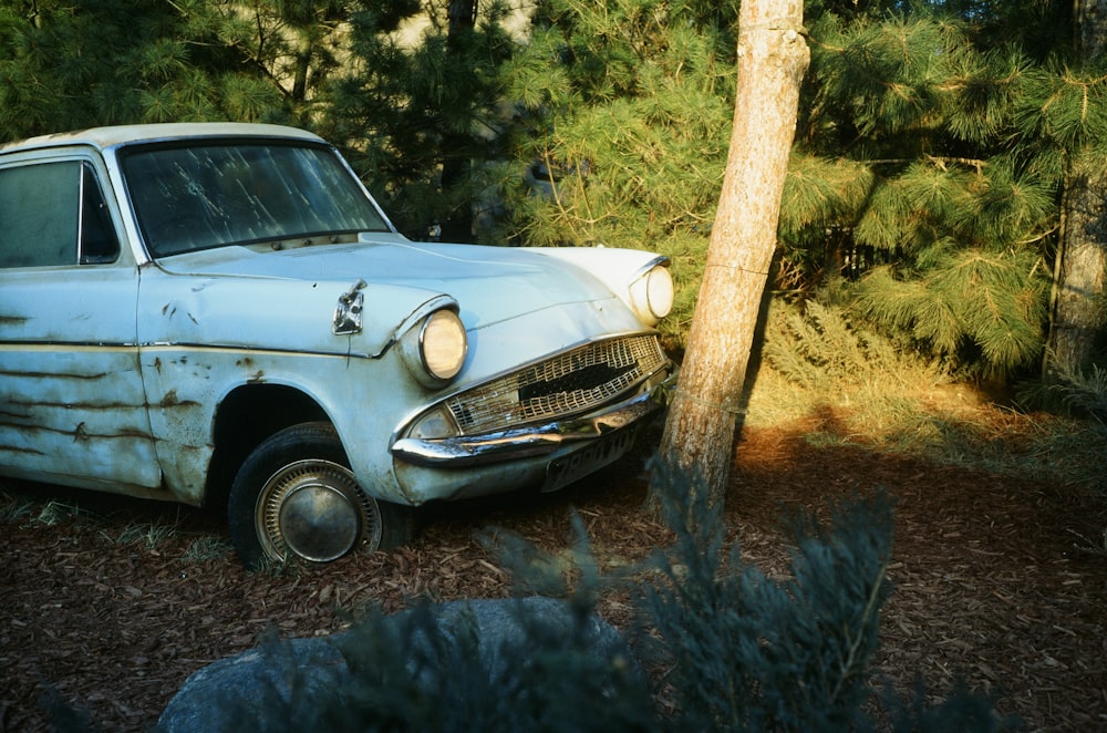 an old car parked next to a tree