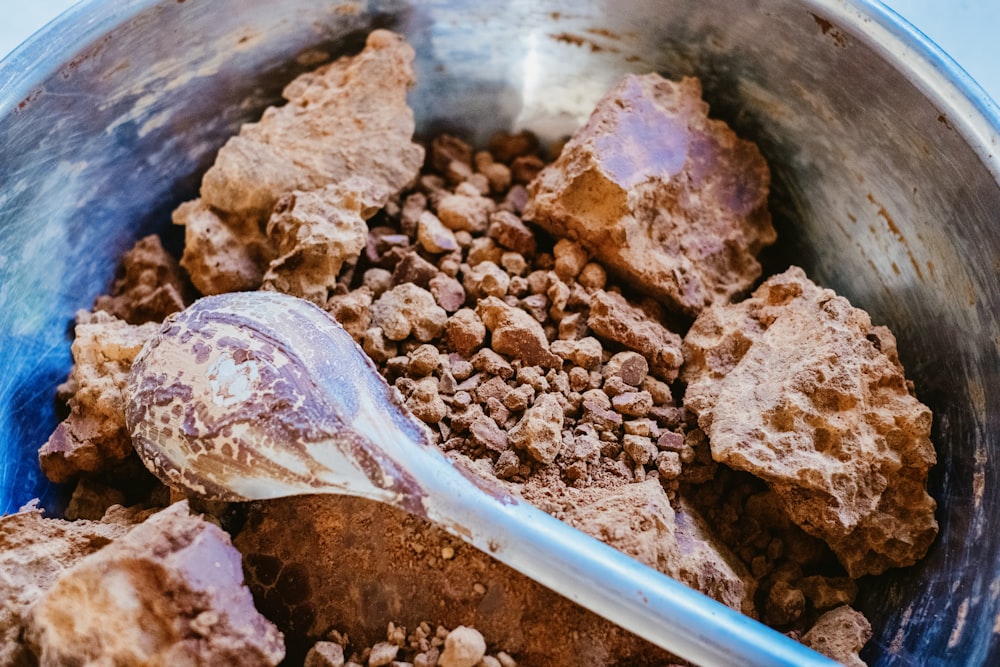 a metal bowl filled with rocks and a spoon