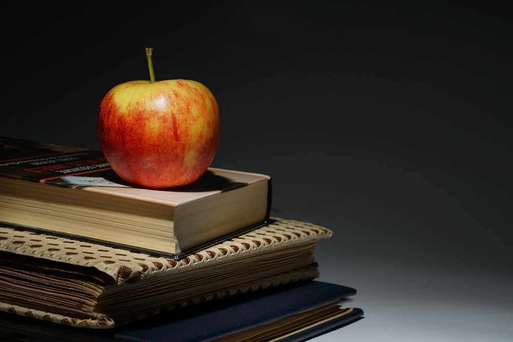 una manzana encima de una pila de libros