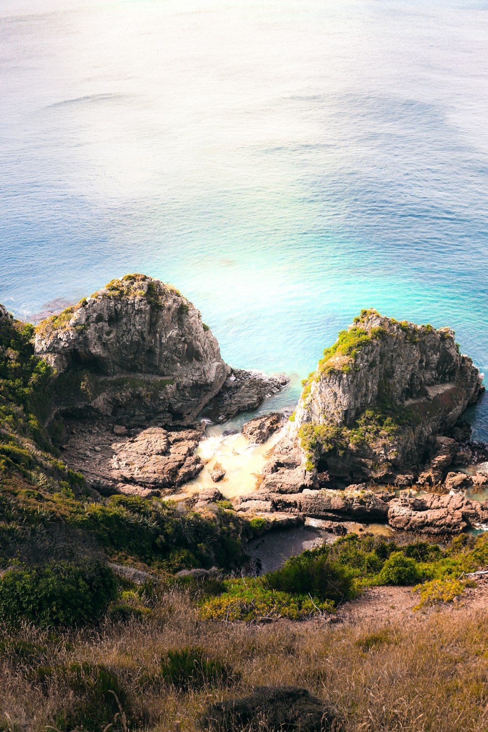 a couple of large rocks sitting on top of a lush green hillside