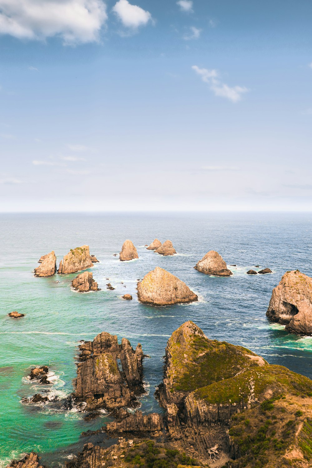 an aerial view of the ocean with rocks in the foreground