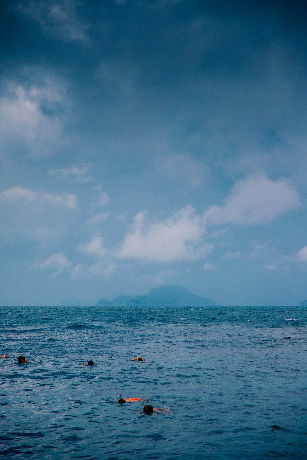 a group of people swimming in the ocean under a cloudy sky