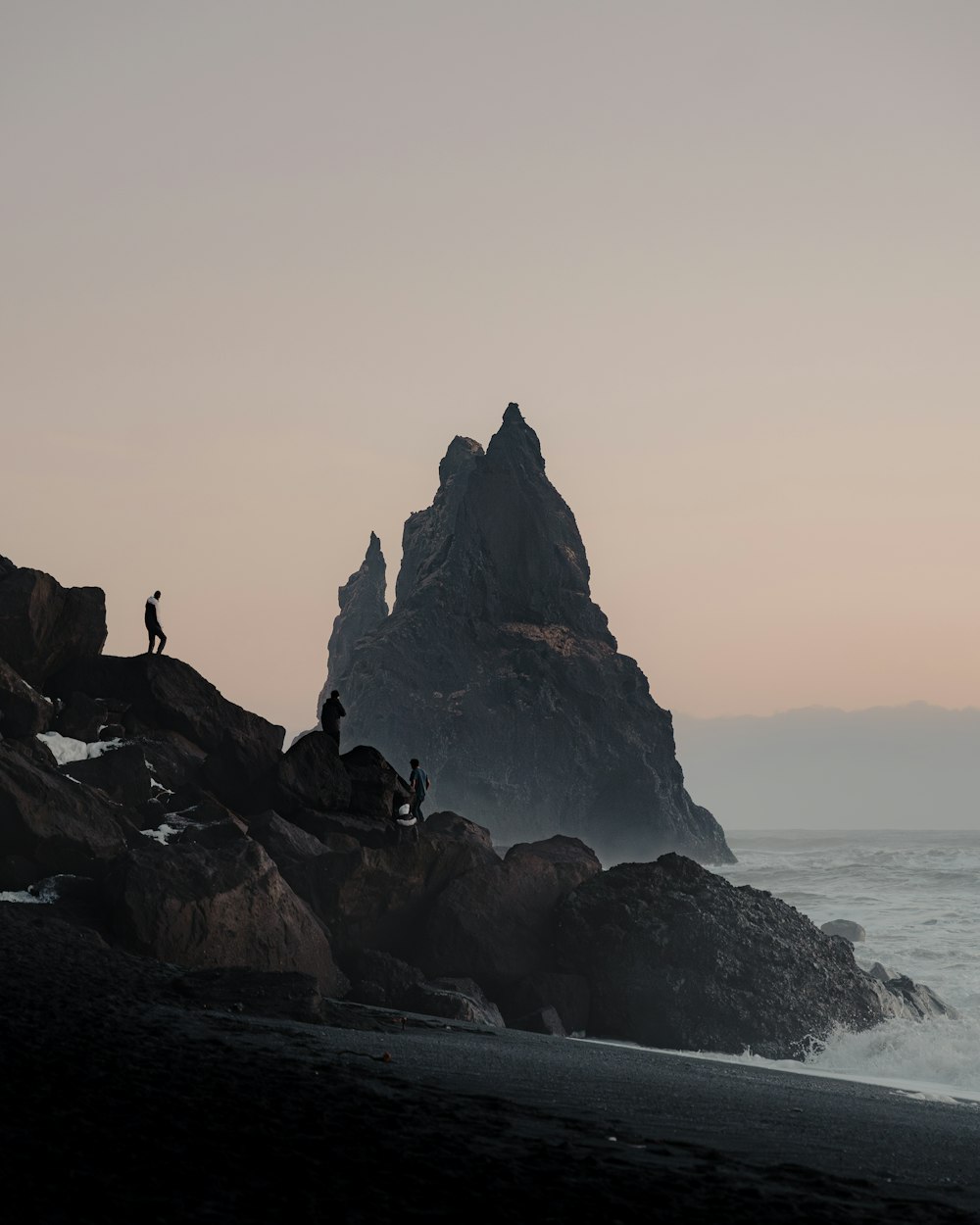 a couple of people standing on top of a rocky beach