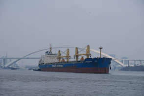 a large cargo ship in the water near a bridge