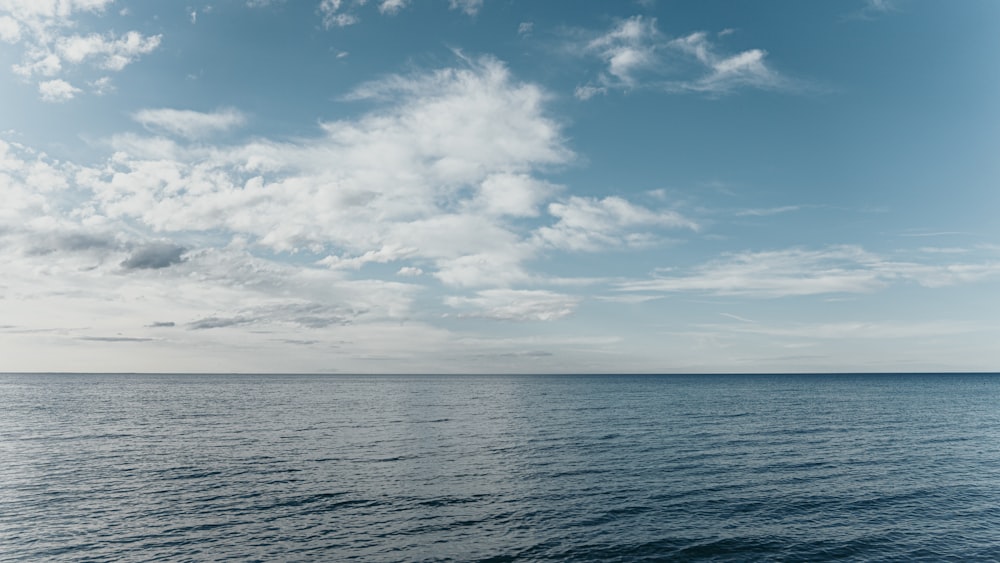 a large body of water under a cloudy blue sky